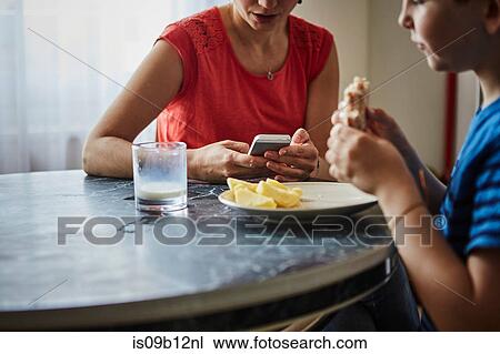 Stock Image - Cropped view of mother and son at dining table. Fotosearch
