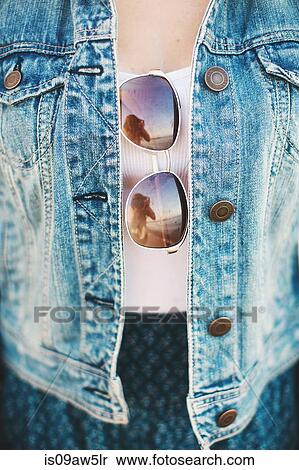 Cropped view of woman mid section wearing denim jacket with sunglasses hanging from top View Large Photo Image Stock Photography - Cropped view of woman mid section wearing denim jacket with sunglasses hanging from top. Fotosearch