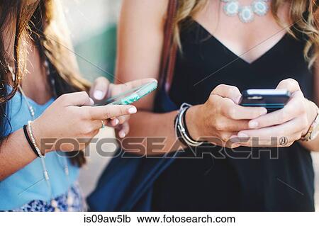 Cropped view of womens mid sections texting on smartphones View Large Photo Image Stock Image - Cropped view of womens mid sections texting on smartphones. Fotosearch