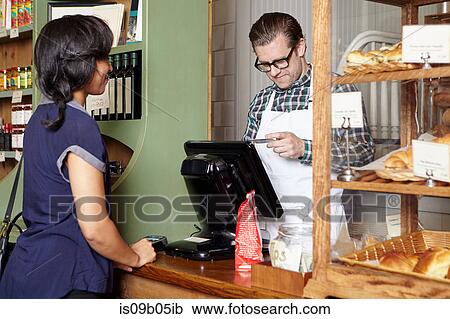 Stock Image - Customer in bakery paying for goods. Fotosearch