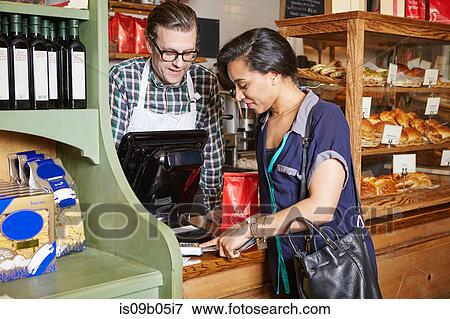Customer in bakery paying for goods, using card machine View Large Photo Image Stock Photo - Customer in bakery paying for goods, using card machine. Fotosearch