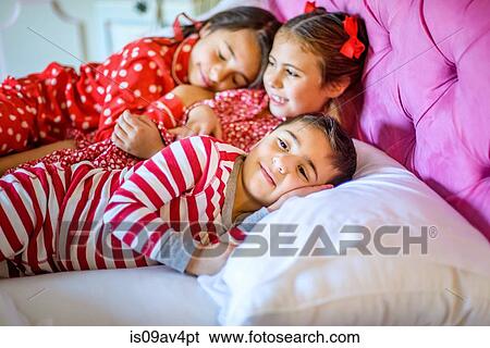 Stock Photograph - Cute boy and two sisters lying in bed. Fotosearch
