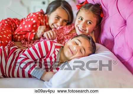 Cute boy and two sisters lying in bed giggling View Large Photo Image Stock Photograph - Cute boy and two sisters lying in bed giggling. Fotosearch