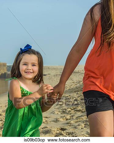 Cute girl holding teenage sisters hand on beach, Asbury Park, New Jersey, USA View Large Photo Image Stock Photography - Cute girl holding teenage sisters hand on beach, Asbury Park, New Jersey, USA. Fotosearch