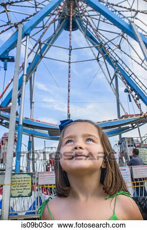 Cute girl looking up in front of ferris wheel at amusement park View Large Photo Image Stock Photography - Cute girl looking up in front of ferris wheel at amusement park. Fotosearch