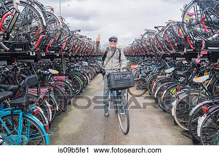 Stock Image - Cyclist on bicycle looking at camera giving thumbs up, Amsterdam, Netherlands. Fotosearch