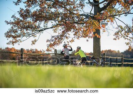 Cyclists resting by fence View Large Photo Image Stock Image - Cyclists resting by fence. Fotosearch