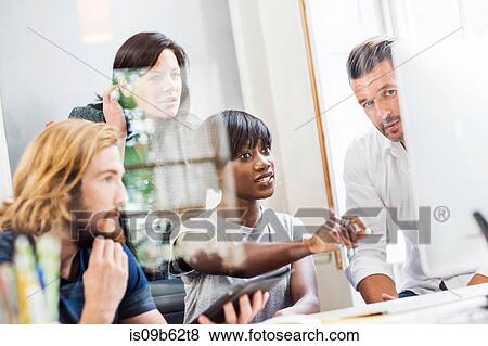 Stock Photo - Design team looking at desktop computer in creative studio. Fotosearch