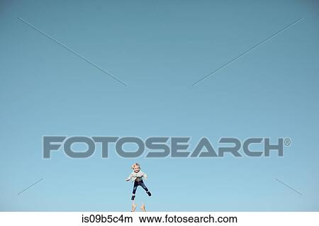 Picture - Distant view of female toddler thrown mid air against vast blue sky. Fotosearch