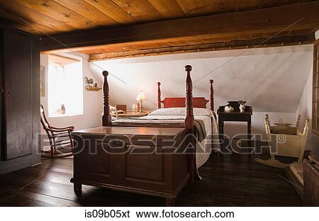 Stock Photograph - Double bed and old wooden storage chest in the master bedroom in old (1785) fieldstone cottage style residential home, Quebec, Canada. Fotosearch