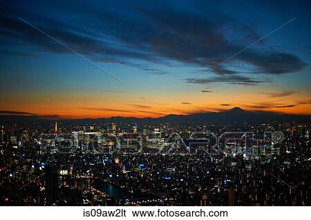 Stock Photograph - Elevated cityscape view with sunset over silhouetted Mount Fuji, Tokyo, Japan. Fotosearch