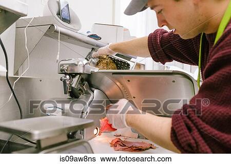 Employee in general store slicing meat in kitchen View Large Photo Image Stock Photograph - Employee in general store slicing meat in kitchen. Fotosearch