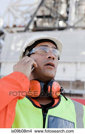Engineer using smartphone on oil rig View Large Photo Image Picture - Engineer using smartphone on oil rig. Fotosearch