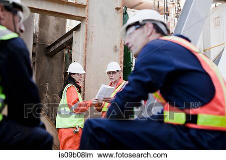 Picture - Engineers in brainstorming session on oil rig. Fotosearch
