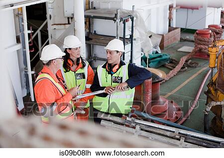 Stock Image - Engineers in brainstorming session on oil rig. Fotosearch