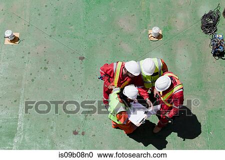 Stock Image - Engineers in brainstorming session on oil rig. Fotosearch