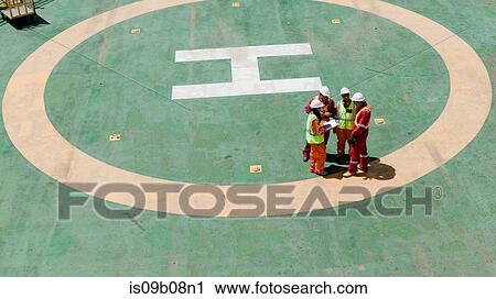Stock Image - Engineers in brainstorming session on oil rig. Fotosearch