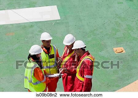 Stock Image - Engineers in brainstorming session on oil rig. Fotosearch