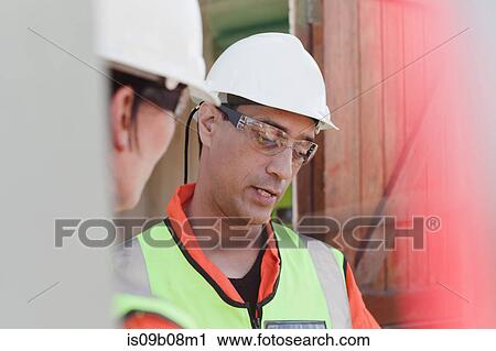 Stock Image - Engineers in discussion on oil rig. Fotosearch
