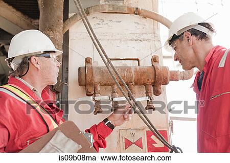 Stock Image - Engineers in discussion on oil rig. Fotosearch