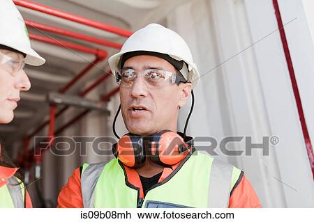 Stock Image - Engineers in discussion on oil rig. Fotosearch