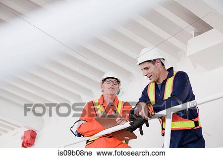 Stock Image - Engineers in discussion on oil rig. Fotosearch