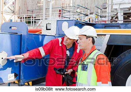 Stock Photograph - Engineers in discussion on oil rig. Fotosearch