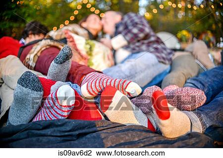 Stock Image - Entwined family socked feet lying on blanket in woods. Fotosearch