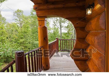 Picture - Exterior of cottage style log home with arch and wooden plank veranda in summer. Fotosearch