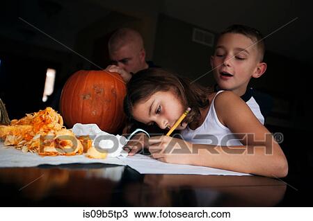 Stock Image - Father and children pumpkin carving. Fotosearch