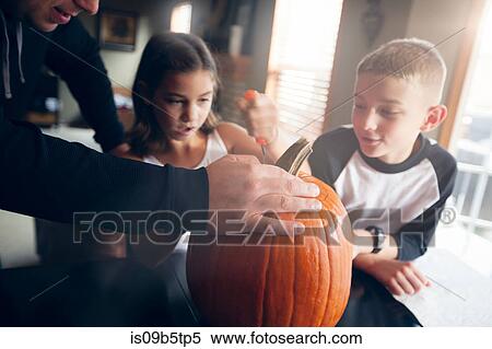 Stock Photography - Father and children pumpkin carving. Fotosearch