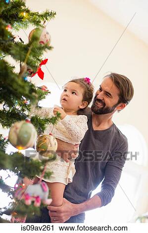 Stock Image - Father and daughter decorating Christmas tree. Fotosearch