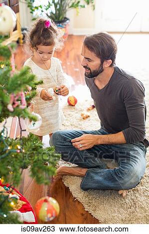 Stock Image - Father and daughter decorating Christmas tree. Fotosearch