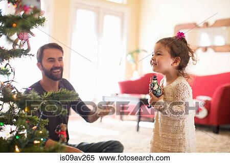 Stock Photography - Father and daughter decorating christmas tree. Fotosearch