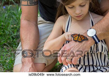 Stock Photography - Father and daughter looking at monarch butterfly. Fotosearch