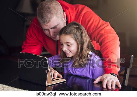 Stock Image - Father and daughter using wireless digital tablet at home. Fotosearch