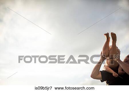 Stock Photo - Father and son fooling around outdoors, father holding son over shoulder. Fotosearch