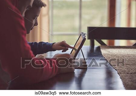 Father and son using wireless digital tablet at home View Large Photo Image Stock Photography - Father and son using wireless digital tablet at home. Fotosearch