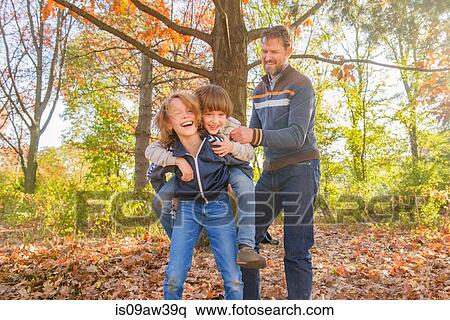 Stock Photography - Father and sons, playing together in forest. Fotosearch