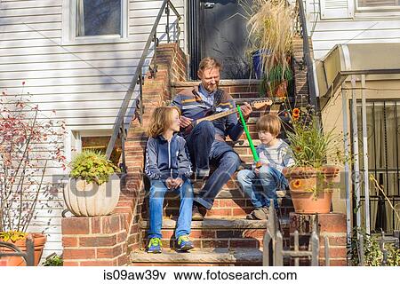 Father and sons sitting together on front steps, father playing guitar View Large Photo Image Stock Photo - Father and sons sitting together on front steps, father playing guitar. Fotosearch
