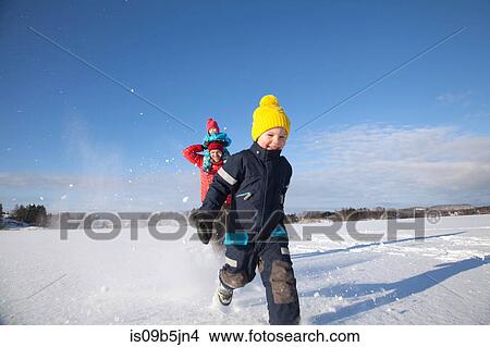 Picture - Father and two sons fooling around, running through snow covered landscape. Fotosearch