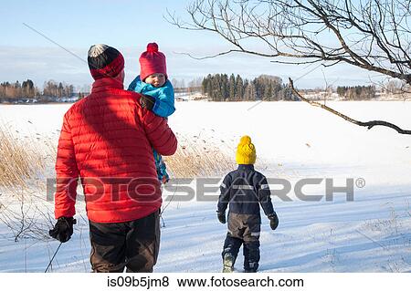 Father and two sons walking in snow covered landscape, rear view View Large Photo Image Stock Photo - Father and two sons walking in snow covered landscape, rear view. Fotosearch