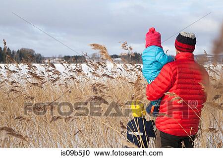 Father and two sons walking through long grass, in snow covered landscape, rear view View Large Photo Image Stock Image - Father and two sons walking through long grass, in snow covered landscape, rear view. Fotosearch