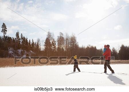 Stock Image - Father and two sons, walking through snow covered landscape. Fotosearch