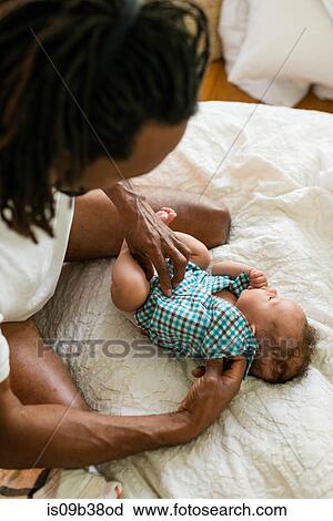 Father dressing up baby in bed View Large Photo Image Stock Image - Father dressing up baby in bed. Fotosearch