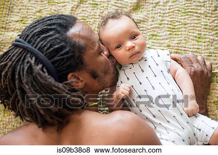Stock Photo - Father kissing baby in bed. Fotosearch