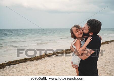 Stock Image - Father kissing daughter on beach, Cancun, Mexico. Fotosearch