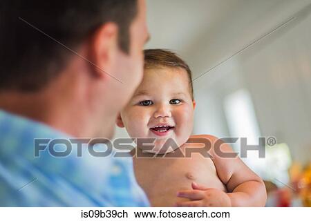 Stock Image - Father playing with toddler in arms. Fotosearch