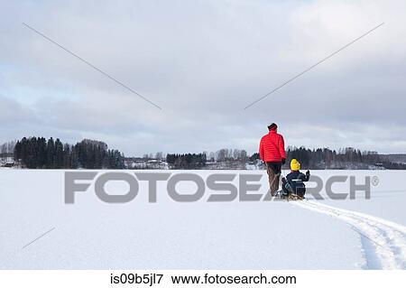 Father pulling sons along on sledge in snow covered landscape, rear view View Large Photo Image Stock Photo - Father pulling sons along on sledge in snow covered landscape, rear view. Fotosearch