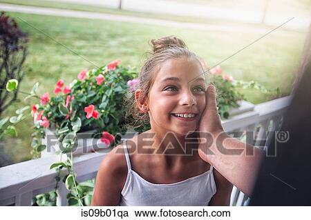 Stock Image - Father touching smiling daughters cheek. Fotosearch